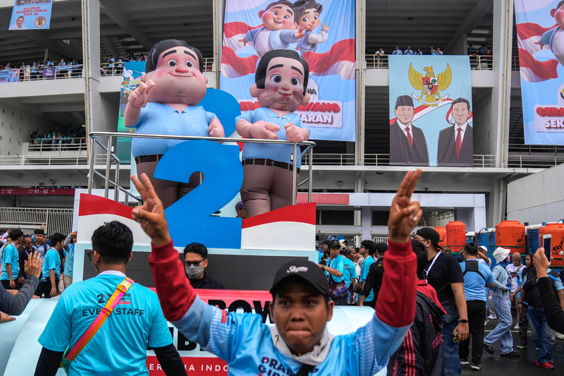 印尼大選前的造勢活動現場，支持者在2號正副總統候選人組合普拉伯沃（左）與吉伯朗（右）的卡通造型吉祥物前手舞足蹈。（攝影／AP Photo／Dita Alangkara／達志影像）