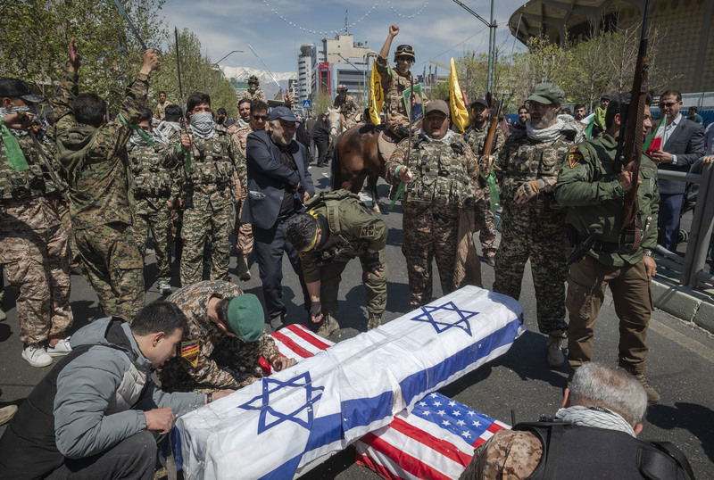 4月5日，在德黑蘭舉行的伊朗革命衛隊將領葬禮上，大批民眾上街抗議以色列及美國要為大馬士革使館空襲事件負責，革命衛隊成員則在街頭以兩國國旗製作棺木道具抗議。（攝影／NurPhoto via Getty Images／Morteza Nikoubazl）