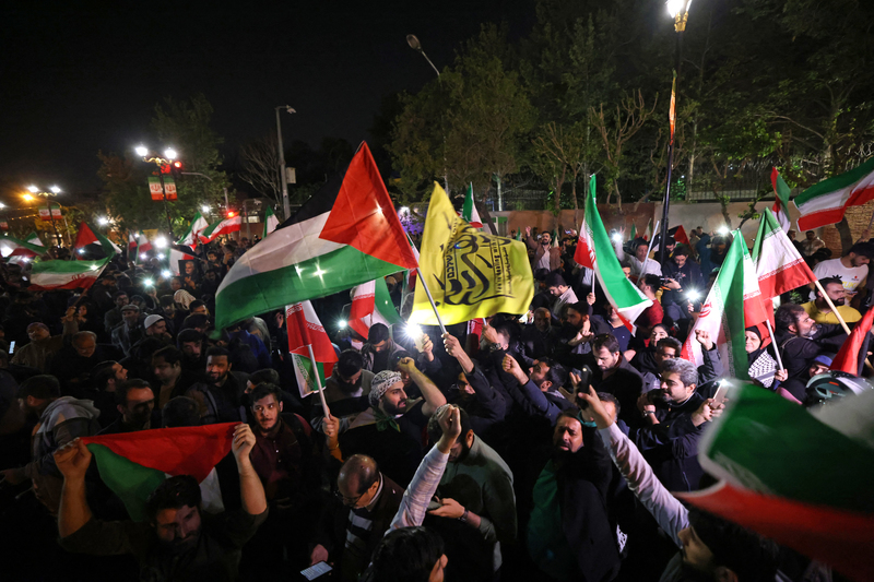 4月14日凌晨，在伊朗對以色列進行無人機與飛彈攻擊後，大批民眾聚集在德黑蘭的英國駐伊朗大使館前，揮舞伊朗革命衛隊及巴勒斯坦國旗示威。（攝影／AFP／ATTA KENARE）