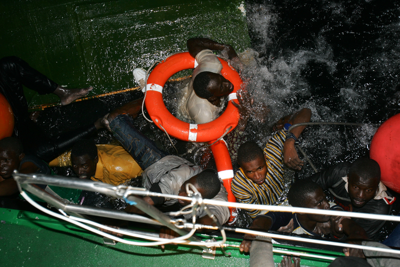 2004年11月12日，在西班牙加納利群島中的富埃特文圖拉島（Fuerteventura）海岸，一場海上救援行動中，因救援船翻覆落海的非洲祕密移民試圖爬上西班牙國民警衛隊的船隻。（攝影／REUTERS／Juan Medina／達志影像）