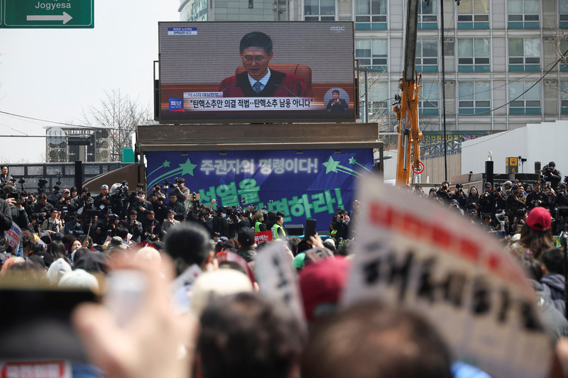2025年4月4日上午，韓國民眾在憲法法院附近舉起標語，等待法院對總統尹錫悅彈劾案的裁決。（攝影／Kim Hong-ji／REUTERS／達志影像）