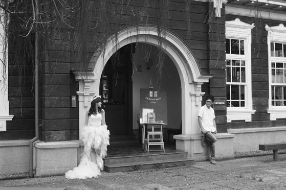 一對年輕夫妻正在以宜蘭的「藍屋」(過去曾是通往宜蘭監獄的門廊)為背景拍攝婚紗照。(圖片來源/黃舒楣於2013年10月拍攝,左岸文化提供)