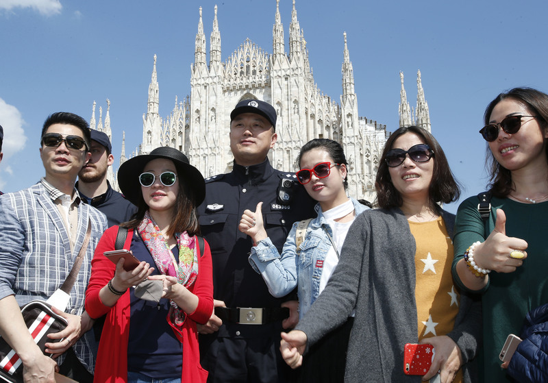 2016年5月3日,一群中國遊客在義大利米蘭主教座堂(Duomo di Milano)前與一名中國警察合影。(攝影/Antonio Calanni/AP Photo/達志影像)