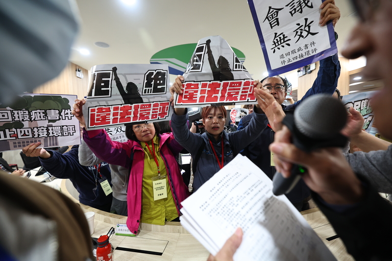 四接環評大會上,反對方與支持方發生激烈肢體衝突,會議主席、環境部次長葉俊宏拿著麥克風在會議室滿場跑、一一詢問環評委員意見,最終更臨時更換會議室才做「修正通過」的決議。(攝影/翁睿坤/中央社)
