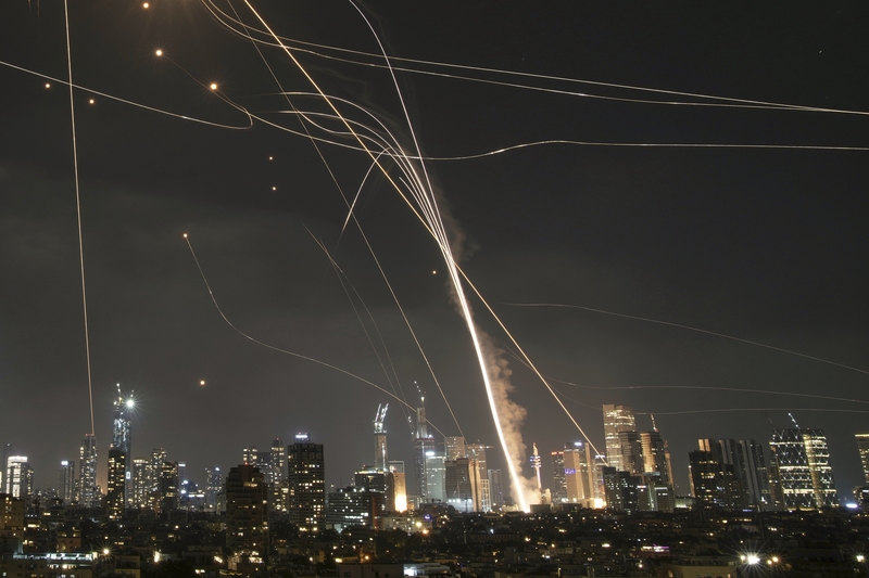 2025年6月13日,以色列特拉維夫(Tel Aviv),一枚來自伊朗的飛彈擊中建築物,同時以色列「鐵穹」(Iron Dome)防空系統升空攔截來襲飛彈。(攝影/Leo Correa/AP Photo/達志影像)