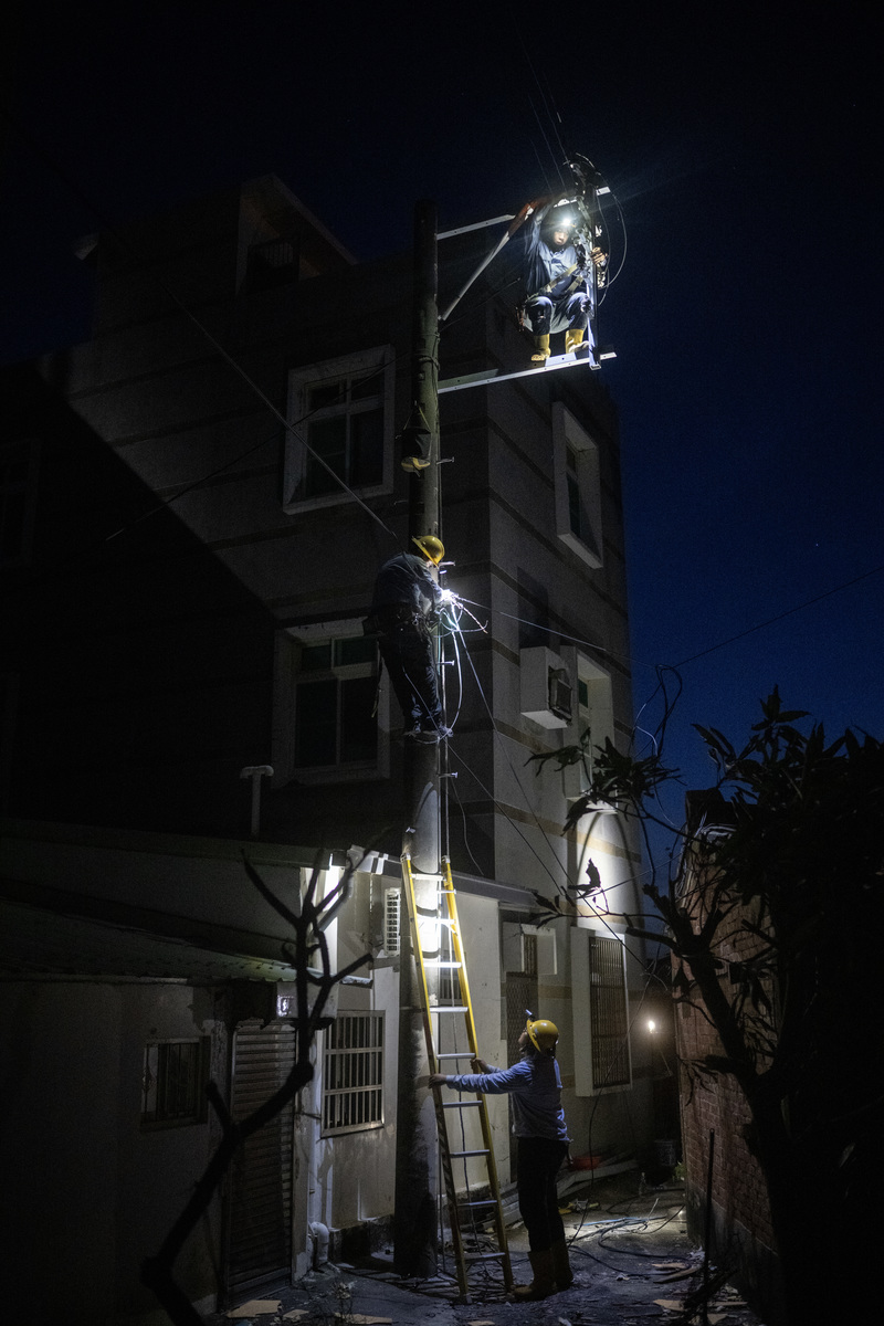 2025年7月13日，台電工人在台南市將軍區的馬沙溝搶修線路，因工程車無法開入狹窄的村落道路，僅能倚靠人力攀爬電線桿進行作業。（攝影／楊子磊）