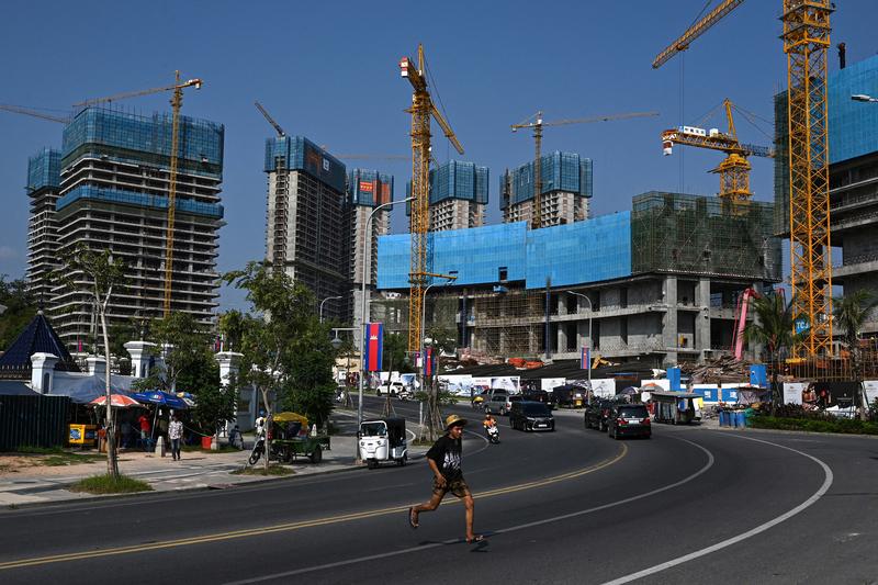 2025年4月8日,柬埔寨西港一名青年跑過尚在施工中的濱海豪華購物度假區。這座曾由寧靜漁村組成的沿海城市,因大量中國投資而劇變,轉型為一座尚未完工的賭博度假城,街頭隨處可見中文招牌。(攝影/Tang Chhin Sothy/AFP)