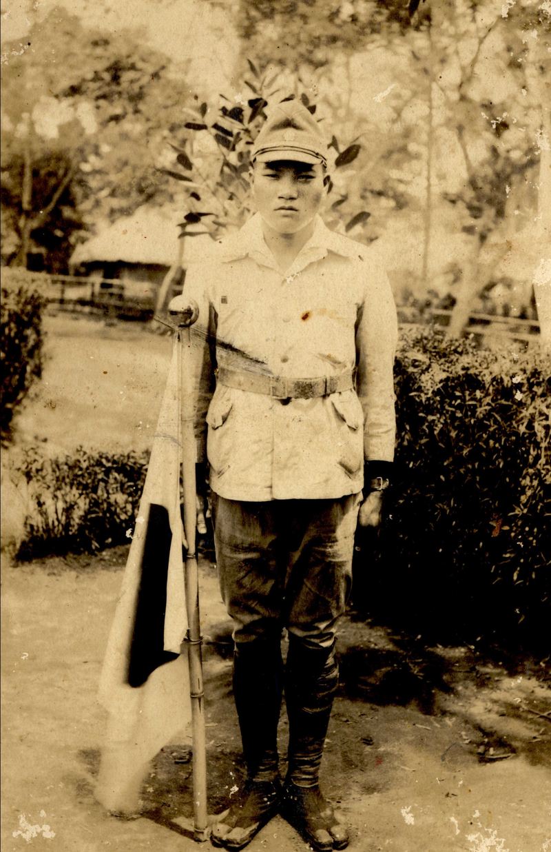 1943年4月,高砂義勇隊出發前,著軍裝與日本國旗拍照留念的洛恩。(圖片提供/蔡政良)