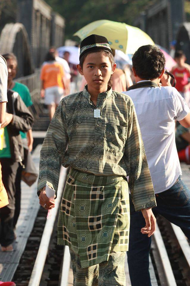 國中時，Ramil參與了一個名為「和平列車」的計畫。火車是貫穿泰國南北最便宜的公共交通工具，載著各式各樣的人。那次Ramil以「和平種子」的身分，與車上乘客分享邊境3省的事。火車的終站是北碧府瀑布站，圖為那時仍會做穆斯林打扮的Ramil走在傳奇的桂河橋上。（圖片提供／Ramil）
