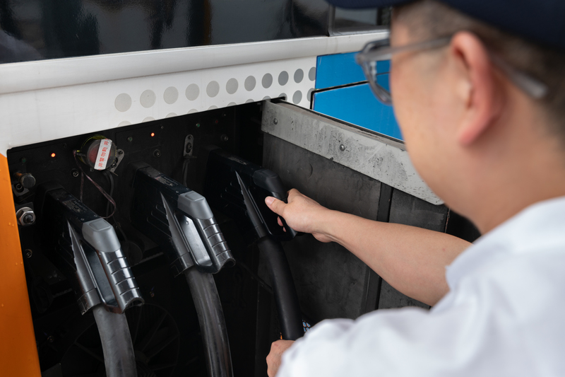 首都客運292路線公車駕駛回到二重站時，需要立即把車子停進充電車位，依照充電樁的指示，依序插入3把充電槍，充滿後要馬上移車才能換下一輛公車充電。（攝影／謝佩穎）