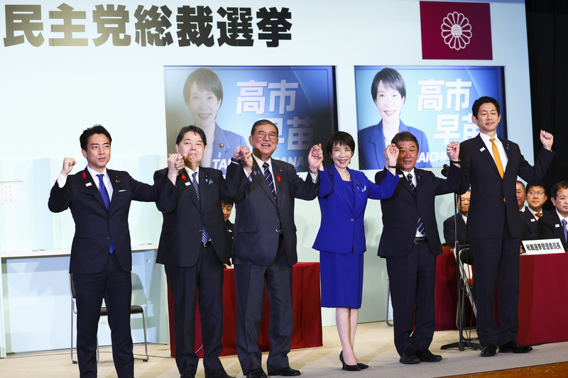 2025年10月4日，日本自民黨新任總裁高市早苗（右3）在選舉中獲勝後，與首相石破茂（右4）以及另外4位候選人小泉進次郎（左起）、林芳正、茂木敏充、小林鷹之上台致意。（攝影／Kim Kyung-Hoon／Pool／Getty Images）