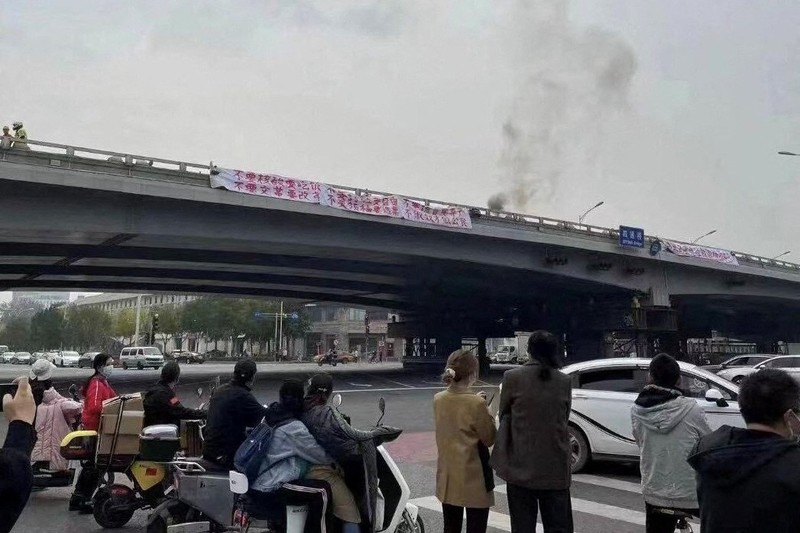 2022年10月13日,中國北京四通橋上掛著帶有抗議標語的布條,現場冒出濃煙引發群眾圍觀,成為「白紙運動」前夕中國公民抗爭的重要象徵事件。(攝影/擷取自社群網路/REUTERS/達志影像)
