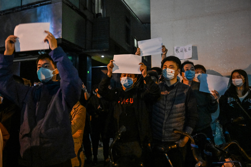 2022年11月27日,中國上海街頭,人們手舉白紙作為抗議象徵,聚集於街頭表達對COVID-19疫情「清零政策」的不滿。(攝影/Hector Retamal/AFP)