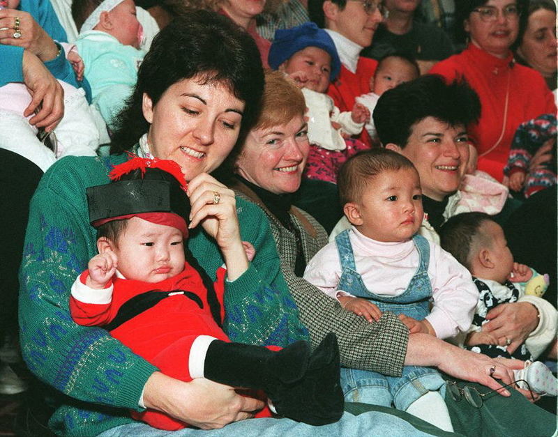 1995年12月,多名加拿大女性在完成領養手續後數日,開心地抱著她們新領養的中國孩童合影。(攝影/ROBYN BE/AFP)