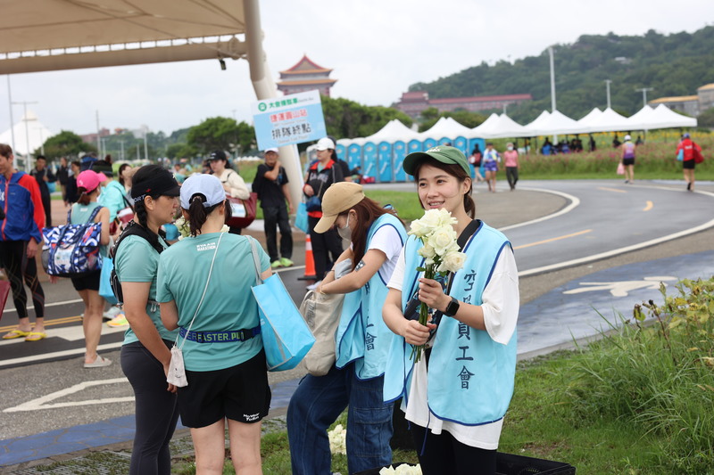 工會會員到長榮馬拉松終點發送白玫瑰花給跑者尋求支持。總在第一線的桃園市空服員職業工會常務理事林昱嘉認為，空服員爭取勞權的馬拉松仍有一段路要跑。（攝影／林雨佑）