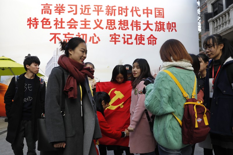 2017年11月19日,一群大學生在上海的中國共產黨第一次全國代表大會紀念館附近與黨旗合照。時值習近平展開其中國共產黨總書記第二個任期,成為自毛澤東逝世以來,中共最積極塑造個人崇拜的領導人。(攝影/Andy Wong/AP Photo/達志影像)