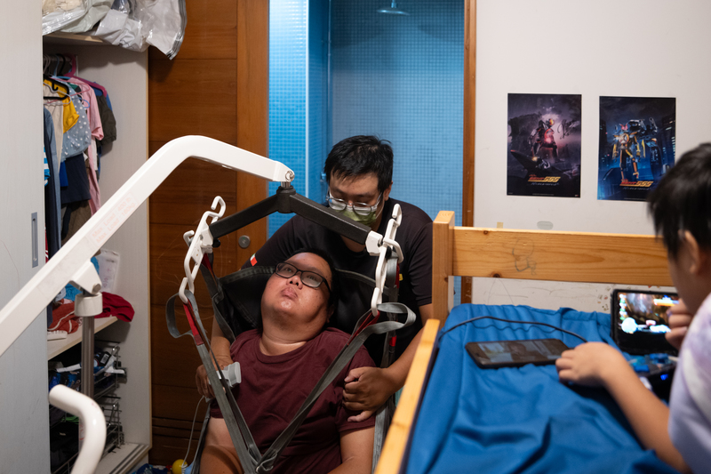 夜間居服員魏力虎,在劉于濟就寢前到家裡為他洗澡、換衣、協助上床 ,正用移位機協助進浴室。(攝影/謝佩穎)