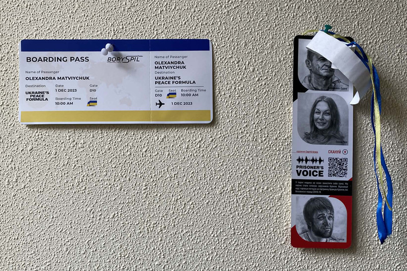 公民自由中心辦公室牆上，左側釘著通往「和平」的紀念機票，右側則是「囚犯之聲」救援書籤。書籤肖像由上至下依序為：退休後定居於克里米亞卻在俄羅斯入侵、占領後被迫害入獄的烏克蘭前海軍軍官杜德卡（Volodymyr Dudka）、於頓巴斯遭囚的藝術史學者佩赫（Olena Piekh），以及被占領當局監禁的克里米亞韃靼運動家薩利耶夫（Seiran Saliev）。（攝影／劉致昕）