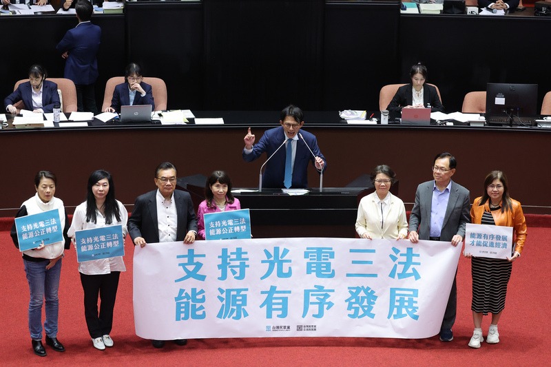 2025年11月14日傍晚，立法院會審理《地質法》第5條修正草案。三讀後，民眾黨團總召黃國昌（中）率黨籍立委於發言台拉起布條，宣布光電3法修正通過。（攝影／翁睿坤／中央社）