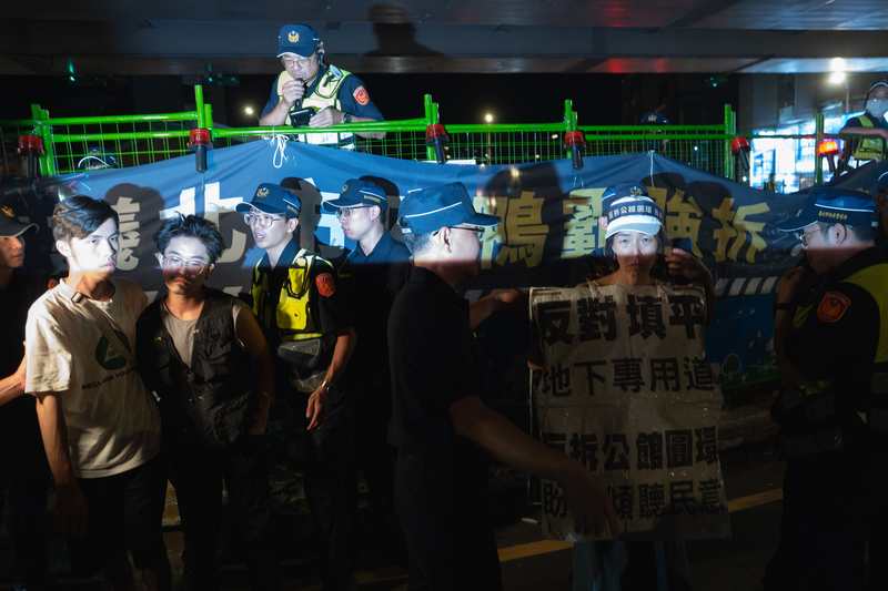 2025年9月12日深夜至13日凌晨，反對拆除公館圓環的群眾跟警方在路口對峙近2小時後，終於獲得警方允許，得以穿越車道和圓環留下合影。但不到2分鐘時間，群眾就被警方驅離回人行道。（攝影／謝佩穎）