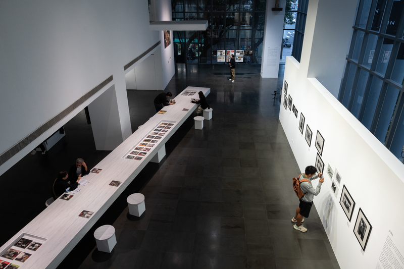 「浮生──《人間》中的報導攝影1985-1989」展場全景。展覽以展間中央的47期《人間》雜誌實體為核心,與環繞四周的紀實影像相互呼應,構築出1980年代台灣社會的視覺檔案。(攝影/謝佩穎)