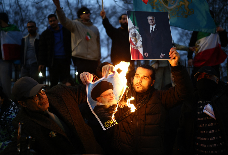 2026年1月12日，在倫敦市中心的伊朗大使館外，示威者正在焚燒伊朗最高領袖哈米尼（Ayatollah Ali Khamenei）的照片，同時高舉前伊朗國王之子芮沙．巴勒維（Reza Pahlavi）的照片。（攝影／Henry Nicholls／AFP）