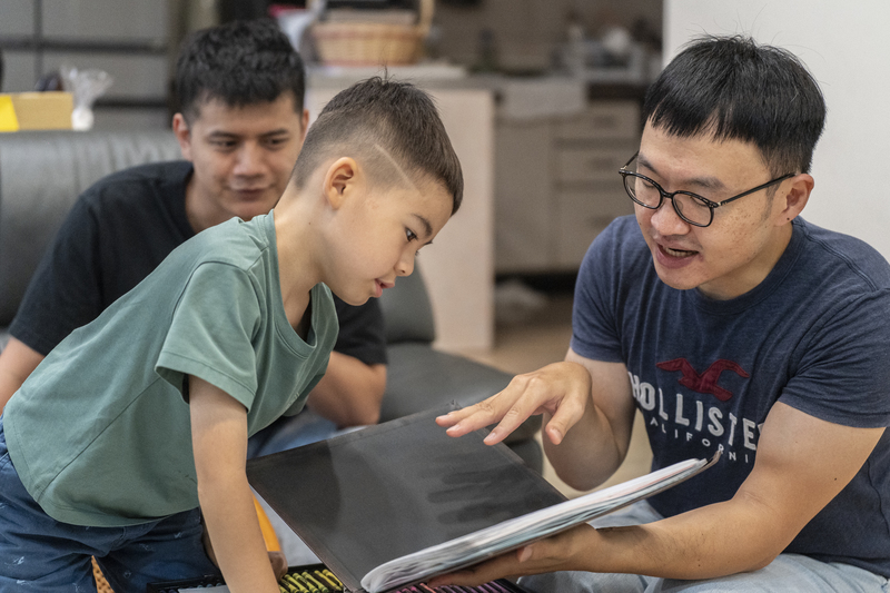 從飛海3歲起,Sean(右)就會帶著飛海(中)共讀這本「身世之書」。(攝影/陳曉威)