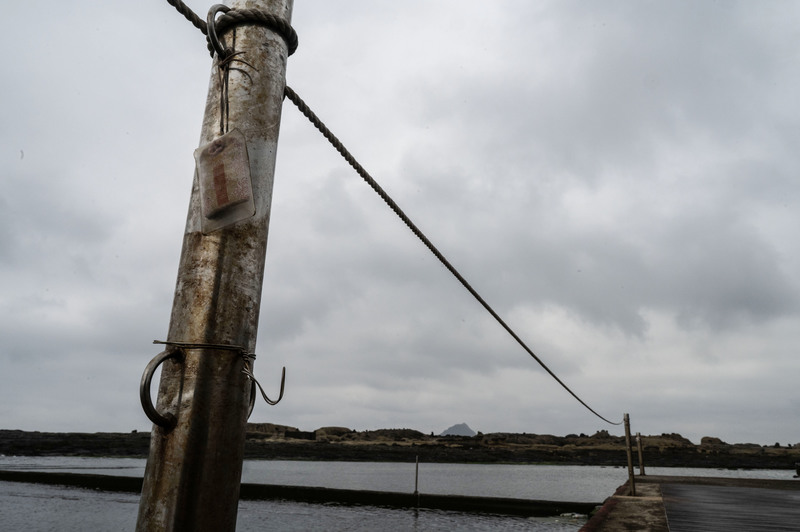 位於基隆的和平島地質公園,一處海岸邊的欄杆上掛著日式的護身符。(攝影/楊子磊)