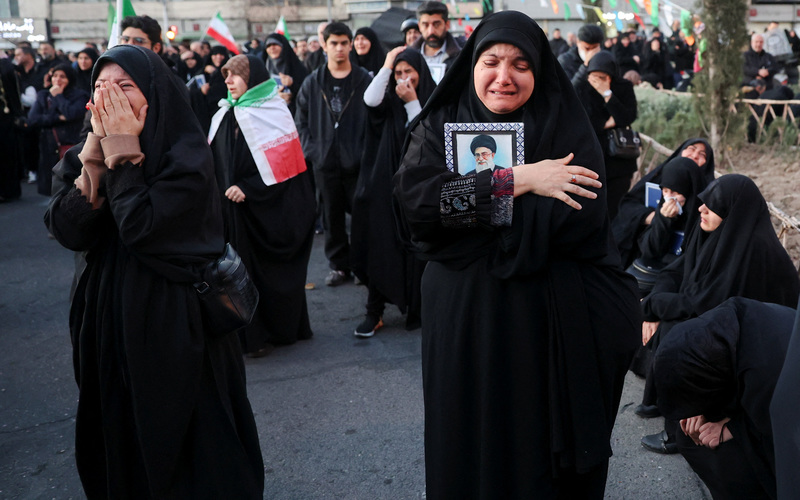 2026年3月1日，在伊朗官方證實最高領袖哈米尼死訊後，大批支持政府的民眾聚集在首都德黑蘭的革命廣場（Enghelab Square）哀悼。畫面中穿著黑色罩袍的婦女難掩悲痛，懷裡緊緊抱著哈米尼的遺像。伊朗政府已宣布全國停班停課，並進入為期40天的國殤期。（攝影／Majid Asgaripour／Reuters／達志影像）