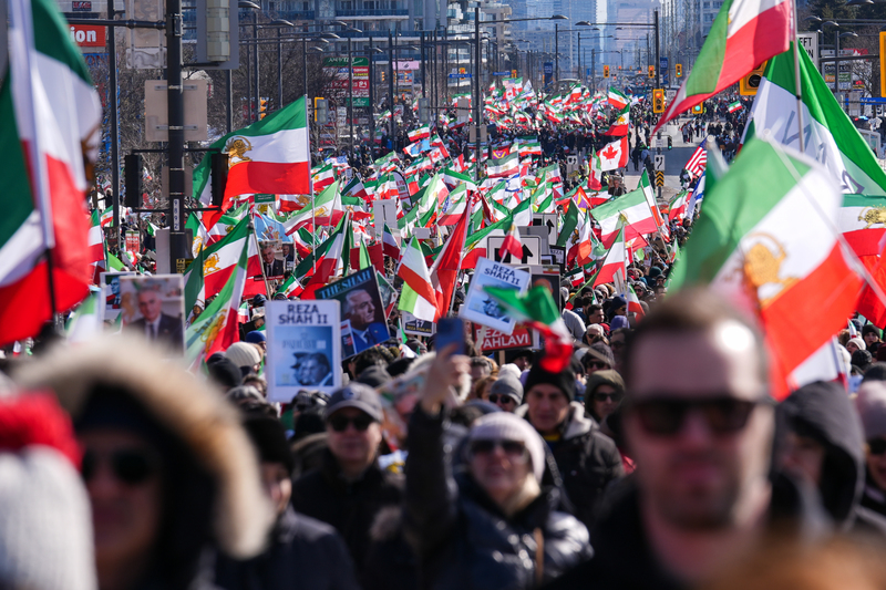 2026年2月28日，大批支持推翻伊朗政權的海外伊朗人與示威者，在加拿大多倫多地區的列治文山市（Richmond Hill）走上街頭參與集會遊行，現場飄揚著象徵前巴勒維王朝的「獅子與太陽」旗幟。隨著美以聯軍發動空襲，海外的伊朗流亡社群紛紛上街，表達對政權更迭的期盼。（攝影／Mert Alper Dervis／Anadolu via Getty Images）