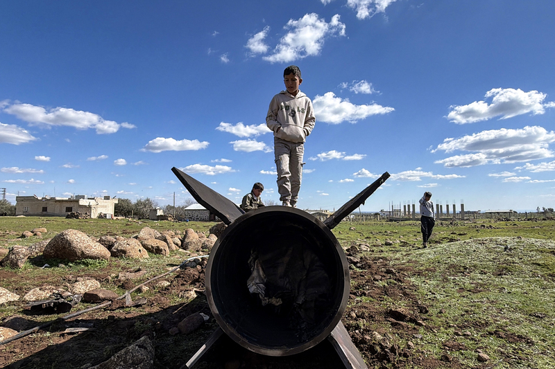 2026年2月28日，在靠近敘利亞南部戈蘭高地（Golan Heights）的庫奈特拉省（Quneitra），幾名敘利亞孩童站在一枚據稱遭以軍攔截的伊朗飛彈殘骸上。同日伊朗向以色列與海灣國家發射大量飛彈，以報復美以聯軍的空襲。（攝影／Bakr Alkasem／AFP）