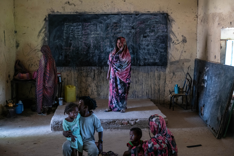 在蘇丹朱奈納（El Geneina）郊區一間廢棄的教室裡，一個來自喀土穆的流離失所家庭，在布滿粉筆痕跡的牆面與破損的家具之間安身。照片攝於2025年7月31日，蘇丹。（攝影／Moises Saman／Magnum Photos；照片提供／無國界醫生）