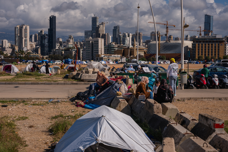 2026年4月6日,因戰事流離失所的黎巴嫩平民們坐在貝魯特海濱一處臨時營地的帳篷外。(攝影/Dimitar Dilkoff/AFP)