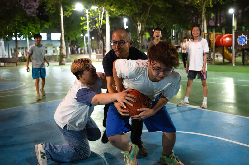 放心窩社會互助協會是陪伴兒少的社區據點,大部分經費都是自籌,總幹事曾子奇(中)在課後陪伴青年打籃球,連在民間單位的他也感受到籠罩在社安網下的咎責文化。(攝影/謝佩穎)