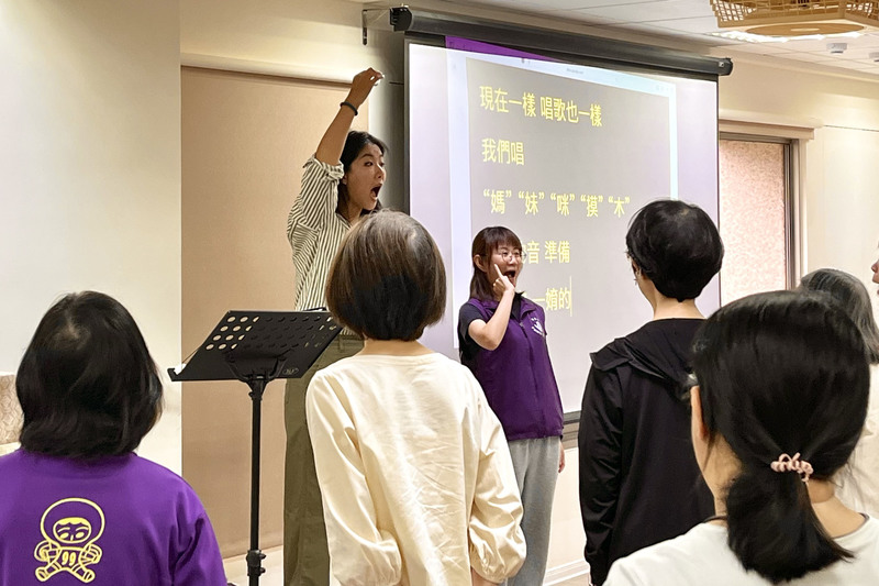 天聽合唱團指揮老師林慧雯用特定的手勢代表不同音高，引導學員開嗓，同時讓學員透過視覺掌握音階起伏，培養指揮與團員間的默契與發聲記憶。（攝影／李香霆）