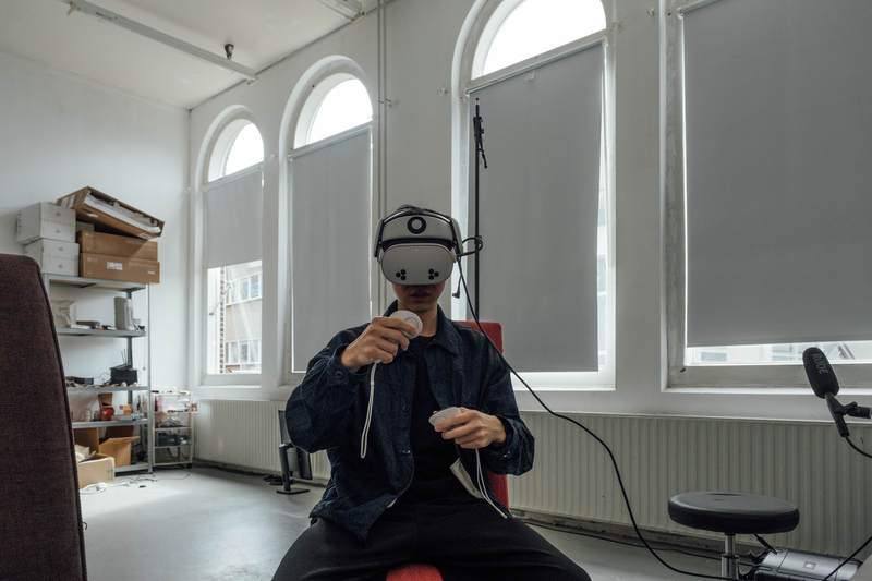 在Rijksakademie工作室中，李亦凡示範他如何以VR眼鏡及控制器進行操偶。（攝影／余志偉）