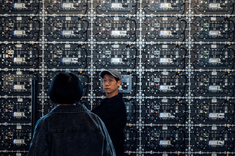 李亦凡（右）正在確認地面與顯示器面板接縫漏光情形。（攝影／余志偉）